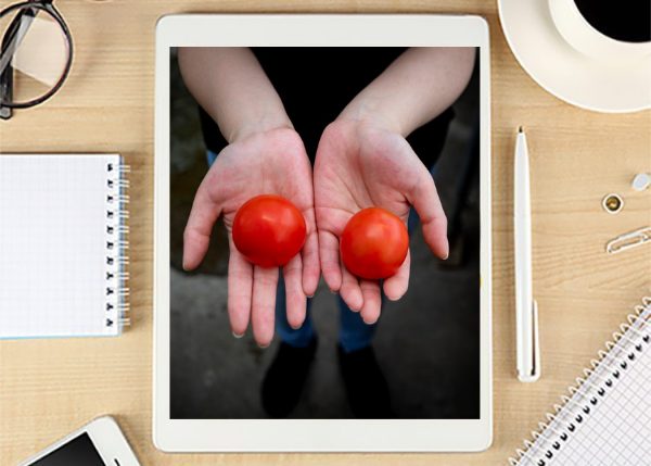 Laptop with hands holding tomatoes