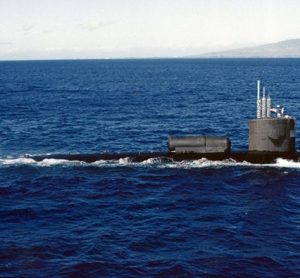A photograph of the USS William H. Bates (SSN-680) submerged in the ocean with light filtering down from the surface. The author, Darin Detwiler, served on this submarine.
