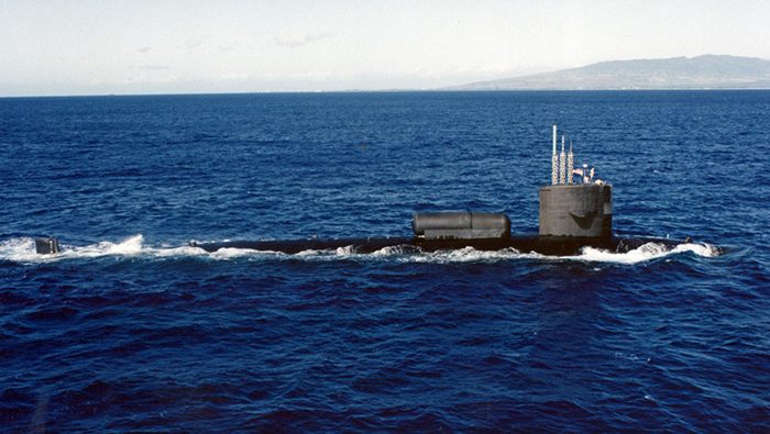 A photograph of the USS William H. Bates (SSN-680) submerged in the ocean with light filtering down from the surface. The author, Darin Detwiler, served on this submarine.