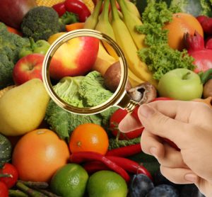 Fresh fruits and vegetables under a magnifying glass, symbolising scrutiny and inspection in global food supply chains.