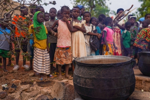 Children in Burkina Faso, Africa, waiting in line for food distribution in 2022, highlighting hunger and food insecurity in low-income regions.