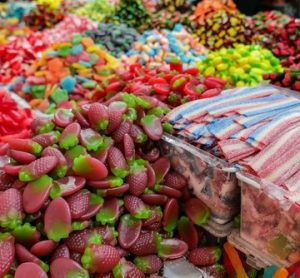 An assortment of colorful candies at a market stall, showing vivid artificial dyes soon to be banned by FDA regulation. Great visual for clean label and natural food trends.